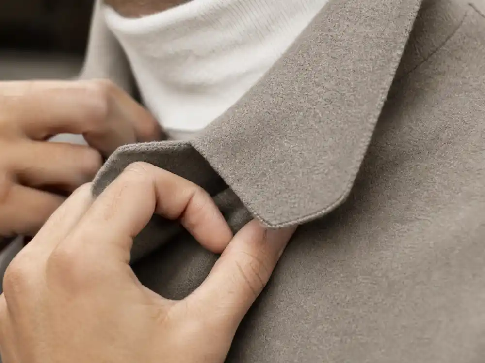 Hands adjusting fine merino wool collar defining stealth wealth celebrity fashion fabric quality and construction details stylists prioritize over monogram visibility