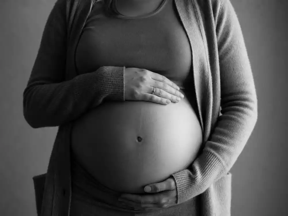 Black-and-white belly hand-grasp for surprise celebrity pregnancy announcements 2025 — torso-only expecting reveal without showing faces
