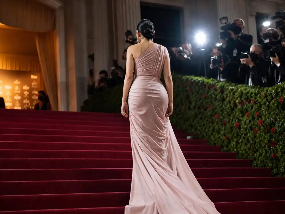 Met Gala museum steps red carpet for surprise celebrity pregnancy announcements 2025 — anonymous couture guest from behind with bump-framed gown silhouette at premiere