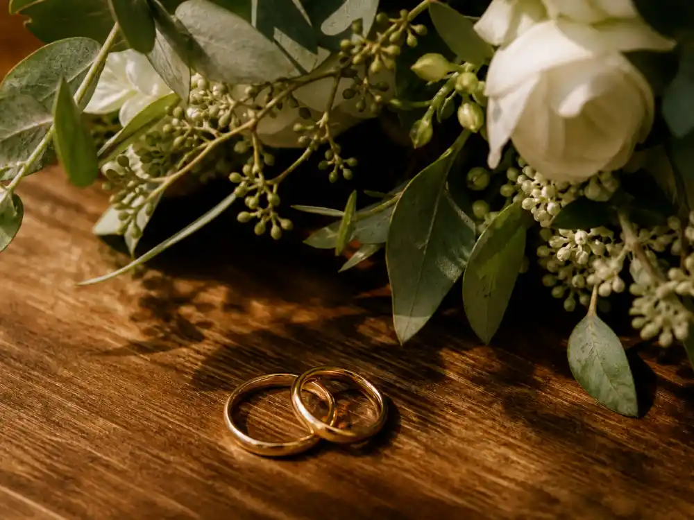 Two wedding rings on a wooden table beside soft candlelight, symbolizing Taylor Lautner marriage to Tay Dome