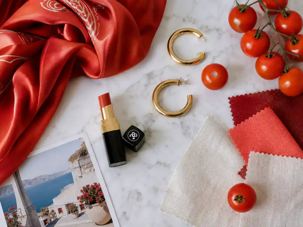 Tomato-red silk scarf coral lipstick and gold hoops flat lay illustrating tomato girl summer celebrity outfits red tone and beauty pairing rules