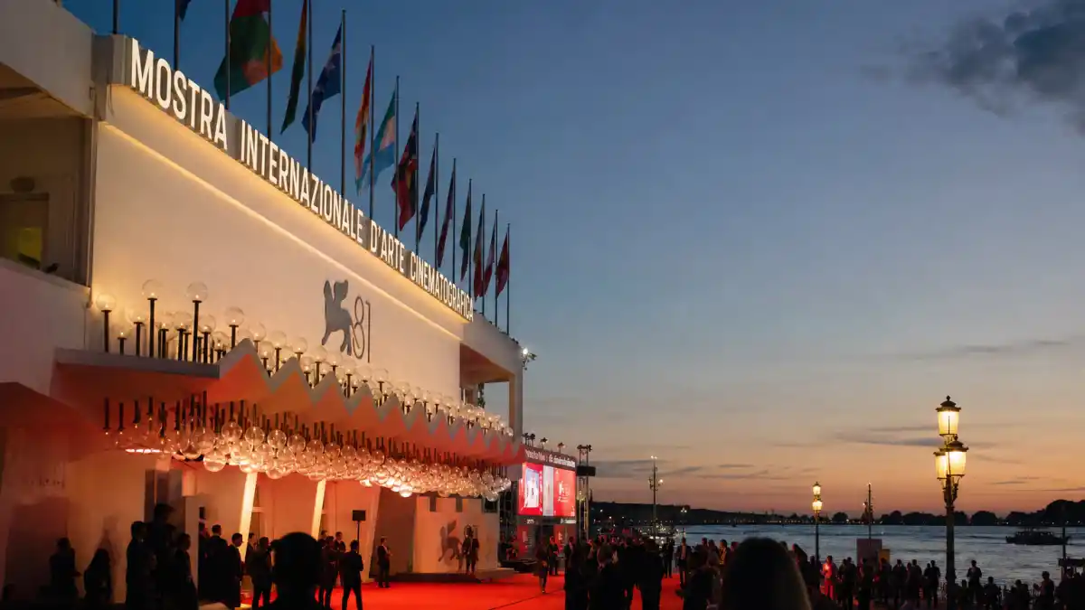 Venice Film Festival explained Golden Lion — Palazzo del Cinema on Lido di Venezia with red carpet and winged lion banners at dusk