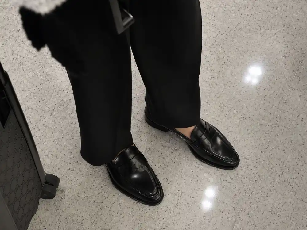 Polished black penny loafers with wide-leg trousers elevating Victoria Beckham airport fashion travel footwear choices
