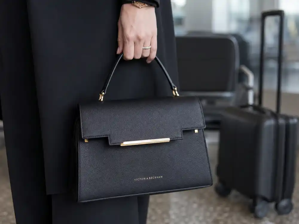 Structured black leather top-handle tote finishing Victoria Beckham airport fashion quiet luxury accessory layer