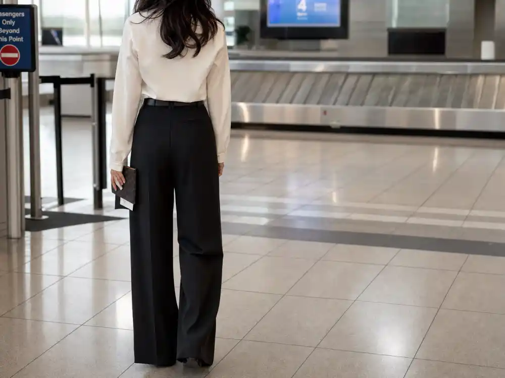 High-waisted black wide-leg trousers with cream blouse defining Victoria Beckham airport fashion proportion discipline