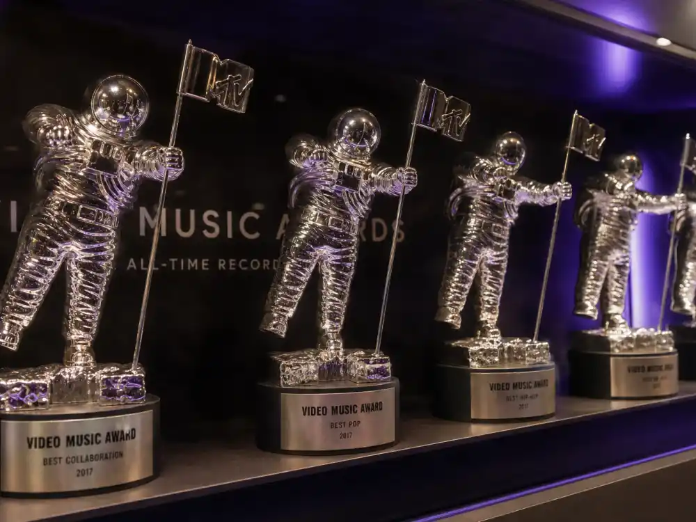 Shelf lined with MTV Moon Person trophies illustrating all-time totals for the most VMAs won by an artist