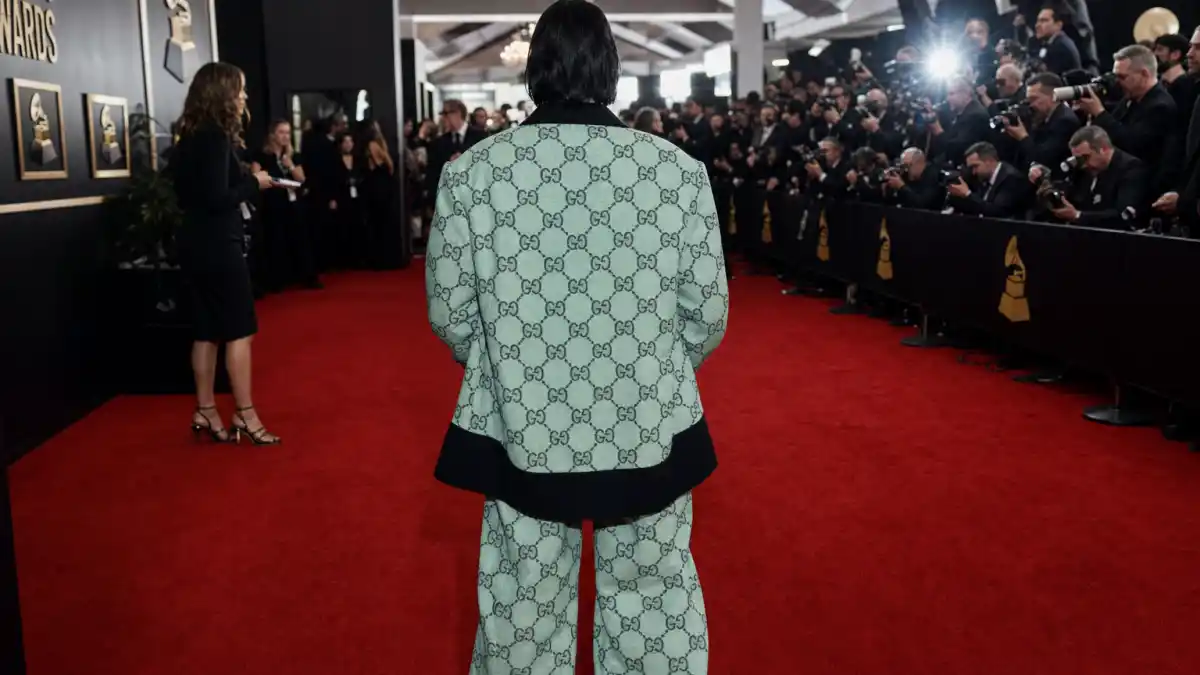 What did Billie Eilish wear to Grammys — oversized Gucci suit on the red carpet seen from behind with camera flashes