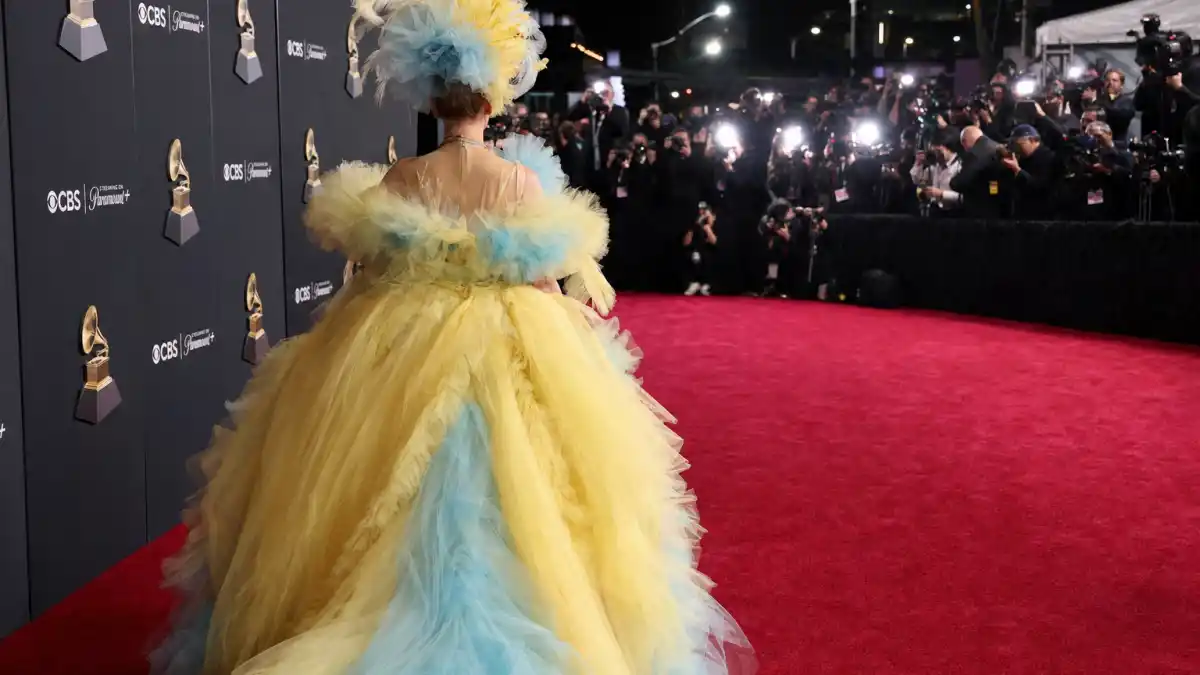 What did Chappell Roan wear to Grammys — vintage Jean Paul Gaultier yellow Degas-print tulle ball gown on the red carpet seen from behind with camera flashes