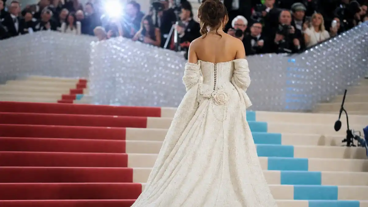 What did Dua Lipa wear to Met Gala — vintage Chanel tweed bridal gown on museum steps seen from behind with camera flashes