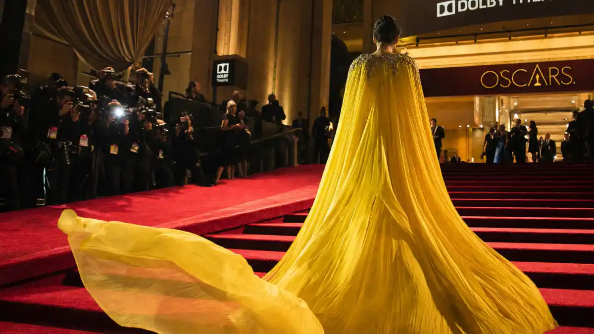 What did Emma Stone wear to Oscars — Louis Vuitton yellow haute couture gown on the red carpet seen from behind with camera flashes
