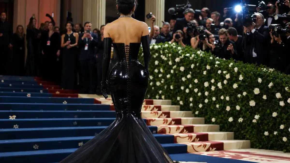 What did Kim Kardashian wear to Met Gala — dramatic latex corset gown on the red carpet with camera flashes and photographers