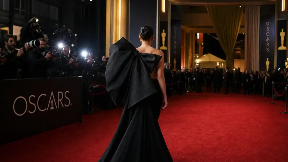 What did Lady Gaga wear to Oscars — dramatic black couture gown with sculptural bow on the red carpet with camera flashes