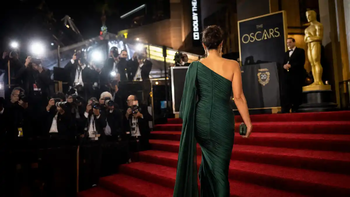 What did Nicole Kidman wear to Oscars — emerald green Balenciaga one-shoulder gown on the red carpet seen from behind with camera flashes