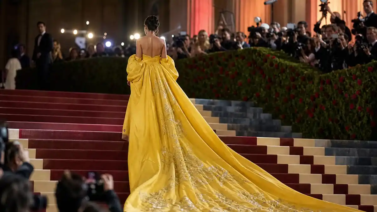 What did Rihanna wear to Met Gala — dramatic yellow couture gown with embroidered train on the museum steps seen from behind