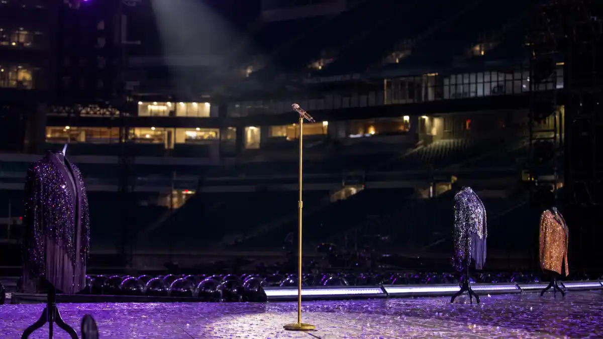What did Taylor Swift wear to Eras Tour — sequin costumes on mannequins at a stadium stage with golden microphone
