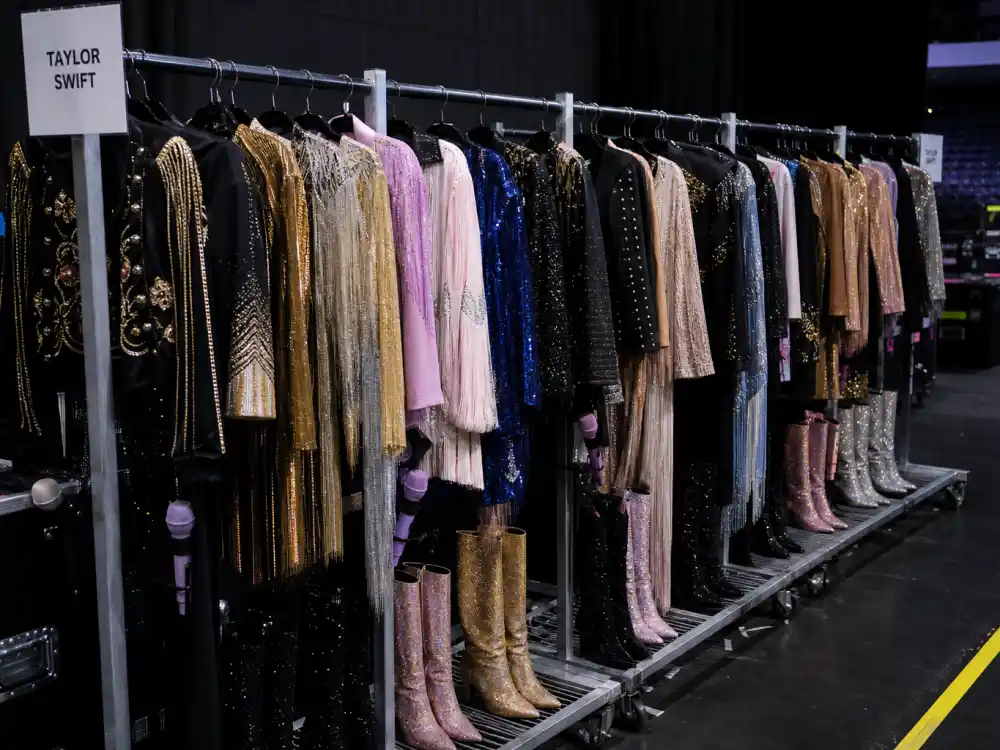Rolling tour wardrobe rack of sparkly bodysuits and boots behind what did Taylor Swift wear to Eras Tour quick changes