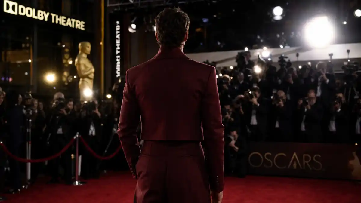 What did Timothee Chalamet wear to Oscars — custom Haider Ackermann red menswear on the red carpet seen from behind with camera flashes