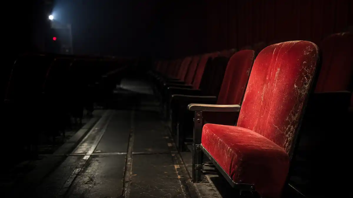 What happened to Brendan Fraser — an empty vintage Hollywood movie theater with worn red velvet seats under a single spotlight