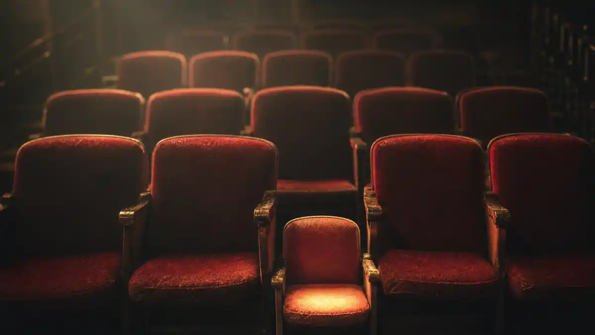 What happened to Mara Wilson — an empty vintage movie theater with a single small child-sized seat lit by a warm spotlight
