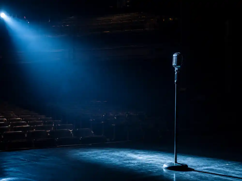 Empty stage with a single spotlighted microphone representing what happened to the Pussycat Dolls now in 2026