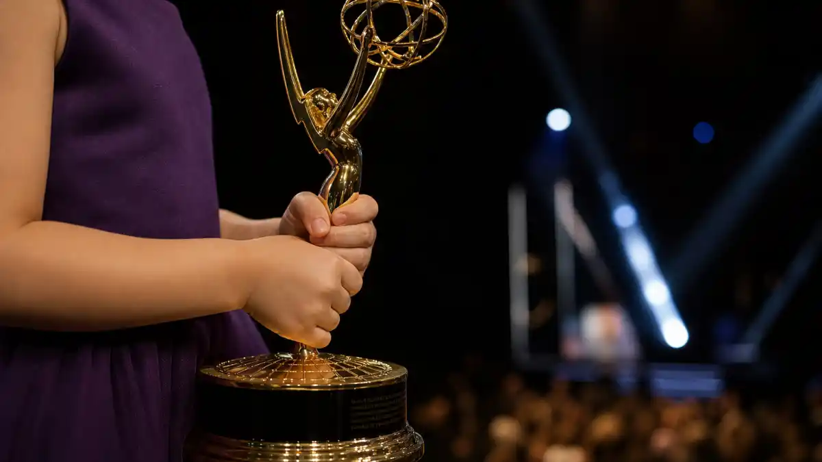 Youngest Emmy winners ever — small hands holding a generic golden television award statuette on a dark Primetime ceremony stage