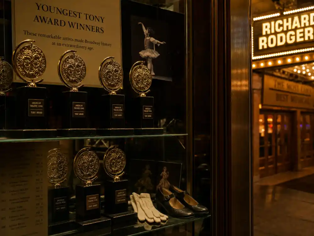 Broadway lobby trophy case with golden Tony Awards documenting youngest Tony Award winners ever age records across decades