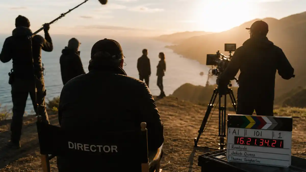 Zoe Kravitz celebrity kid turned A-list star — indie film set from behind with anonymous crew silhouettes at coastal location editorial milestone without identifiable faces