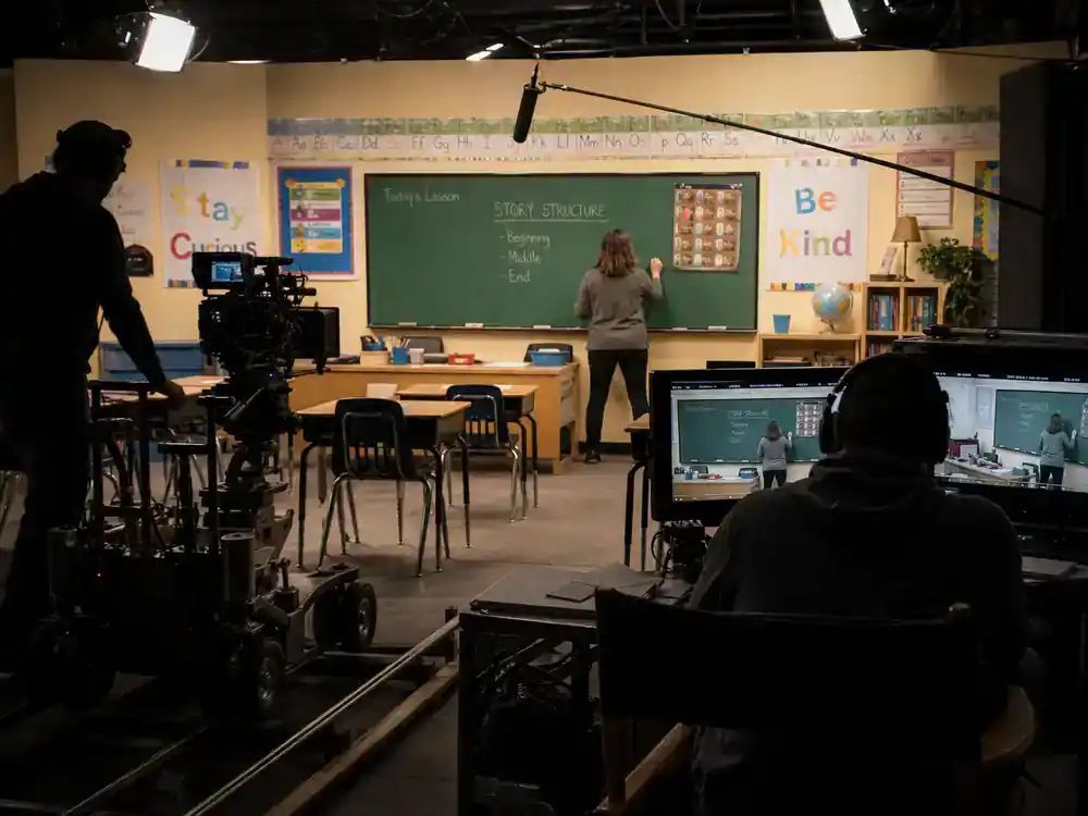 Abbott Elementary season 5 cast guide filming — mockumentary classroom soundstage with camera dolly boom mic and director silhouette
