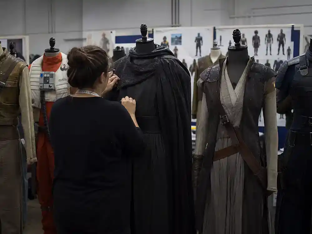 actors who played multiple Marvel characters franchise crossover — film costume department with generic hero outfits on mannequins, tailor adjusting from behind
