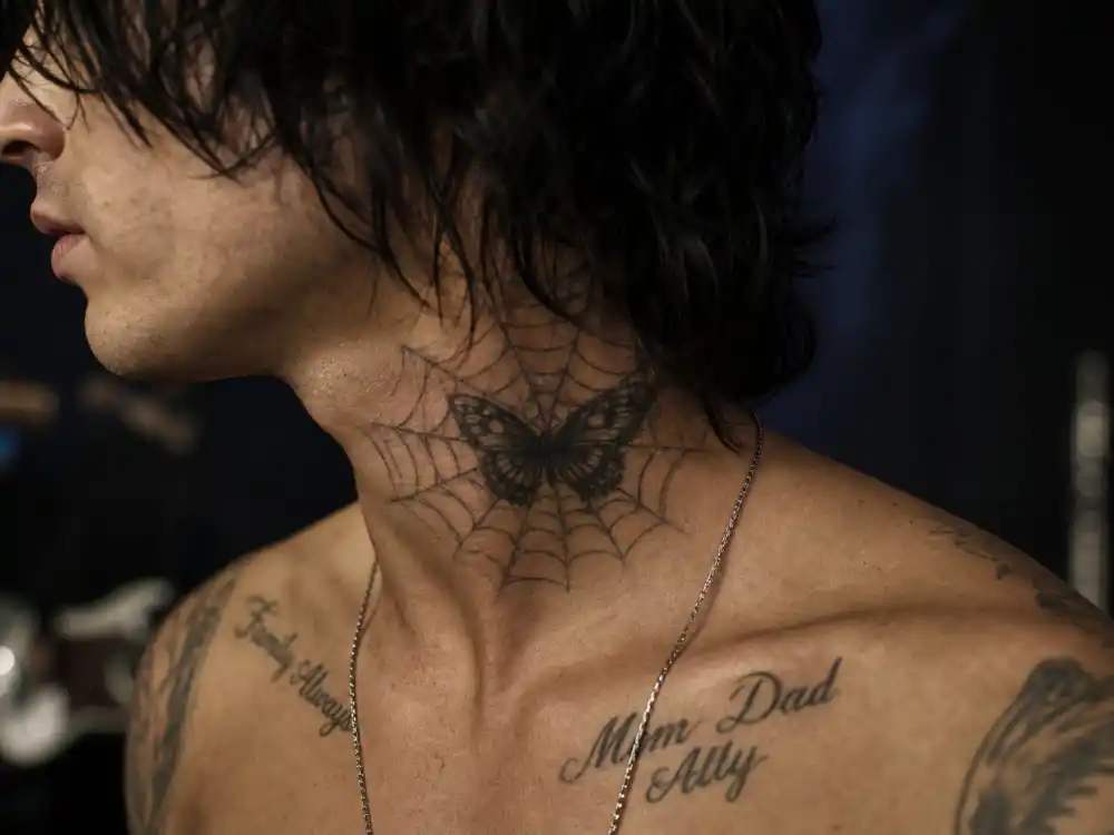 Adam Levine tattoos and their meanings neck ink — butterfly spiderweb and family script collarbone tattoos profile close-up