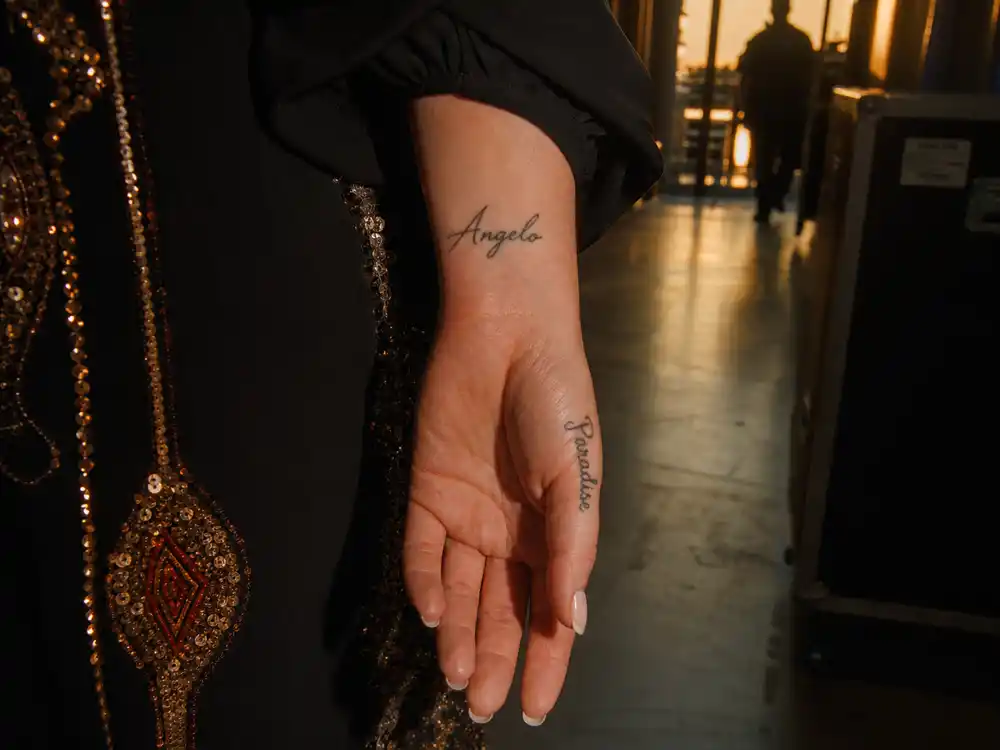Adele tattoos and their meanings Angelo paradise — script Angelo name on right hand and paradise on left hand close-up at Bang Bang NYC studio