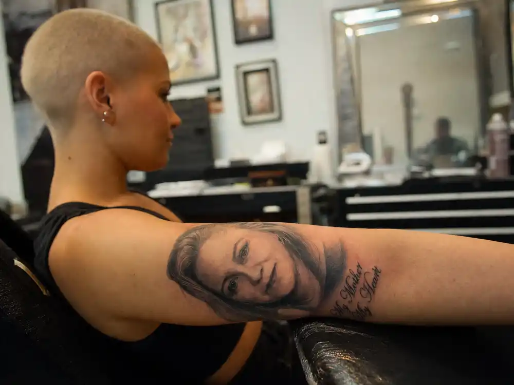 Amber Rose tattoos and their meanings — black-and-grey mother portrait tattoo on inner left arm photographed from side angle