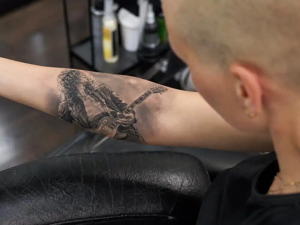 Amber Rose tattoos and their meanings — detailed Slash guitarist portrait tattoo on inner left forearm in studio close-up