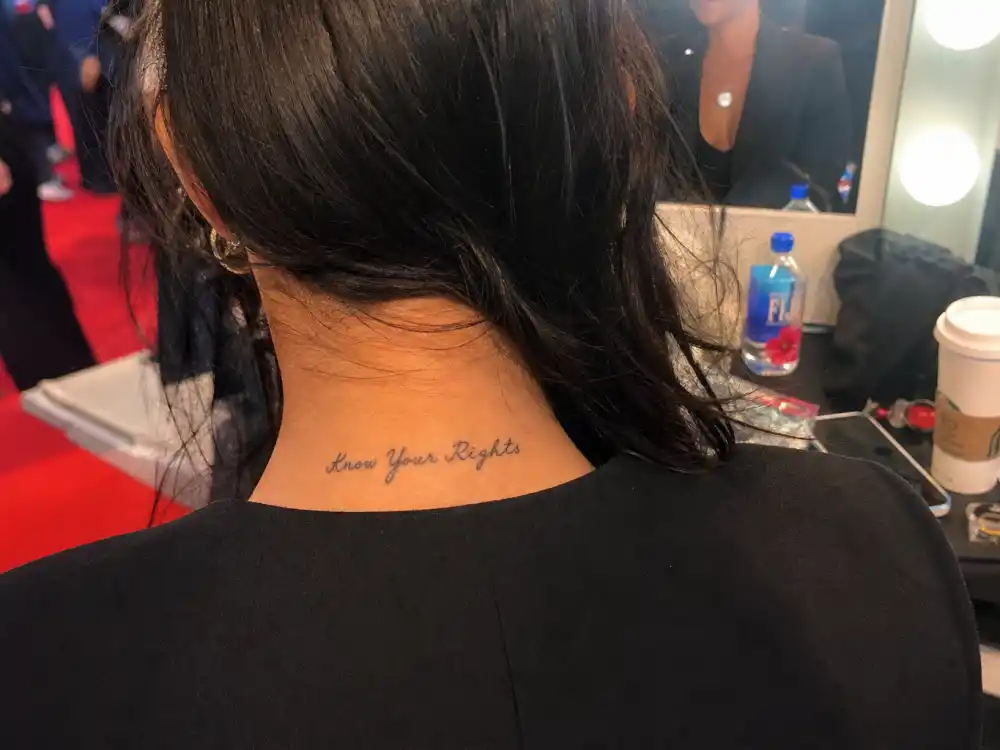 Angelina Jolie tattoos and their meanings — Know Your Rights script tattoo on back of neck photographed over-shoulder in backstage mirror