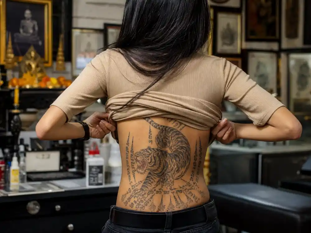 Angelina Jolie tattoos and their meanings — Bengal tiger sak yant tattoo on lower back in traditional Thai style at Bangkok parlor