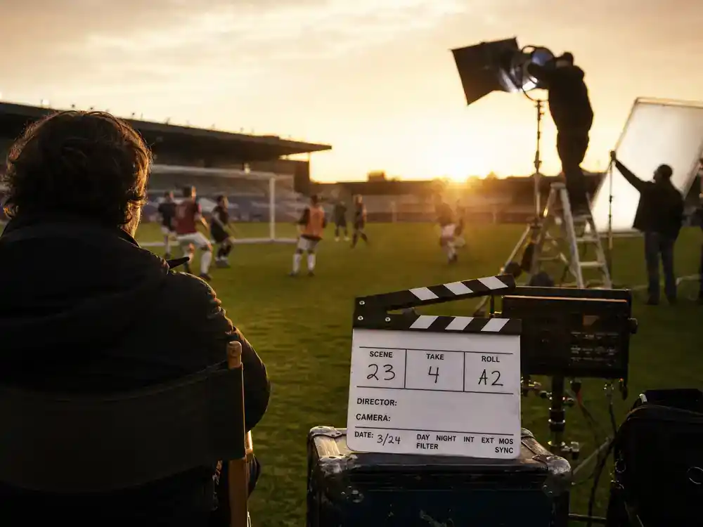Apple TV Plus 2026 shows and cast guide Ted Lasso — soccer field film set with clapperboard and director chair silhouettes on sports comedy TV production