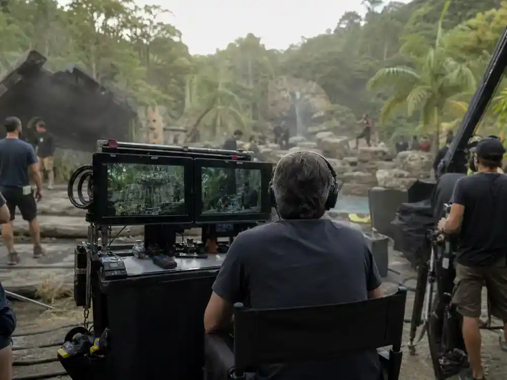 Avatar 3 filming locations and cast updates James Cameron production — director chair on blockbuster set with monitors and tropical forest backdrop from behind