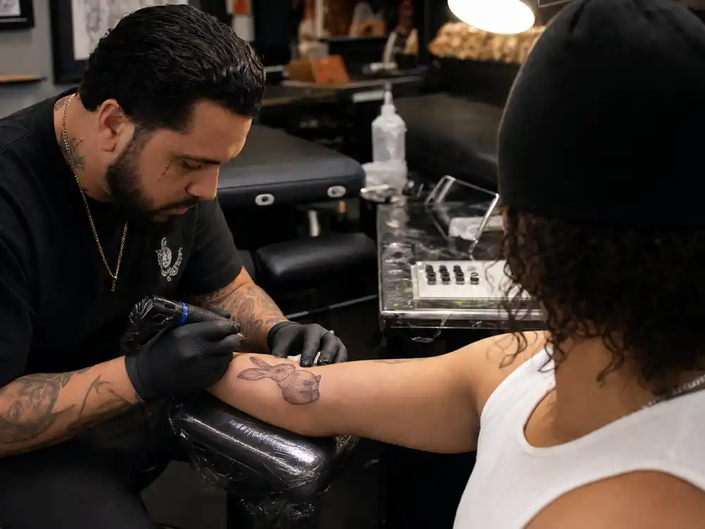 Bad Bunny tattoos and their meanings — tattoo artist inking rabbit tattoo on Puerto Rican musician forearm during professional studio session