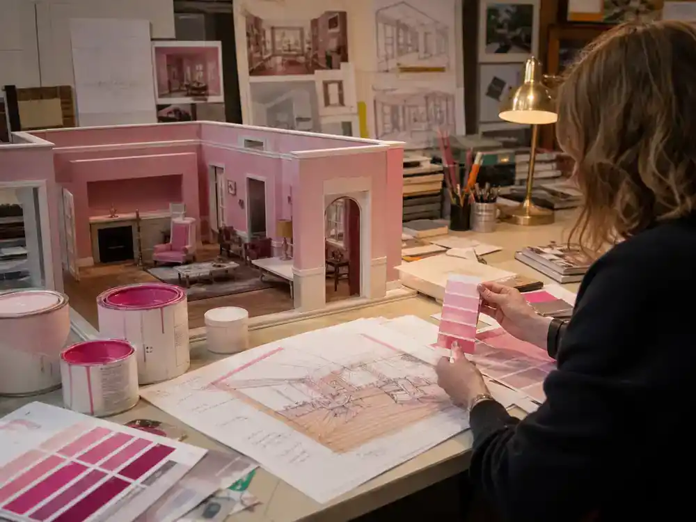 Barbie movie filming locations and set design pink palette — production designer reviewing magenta paint swatches and miniature set model in art department office