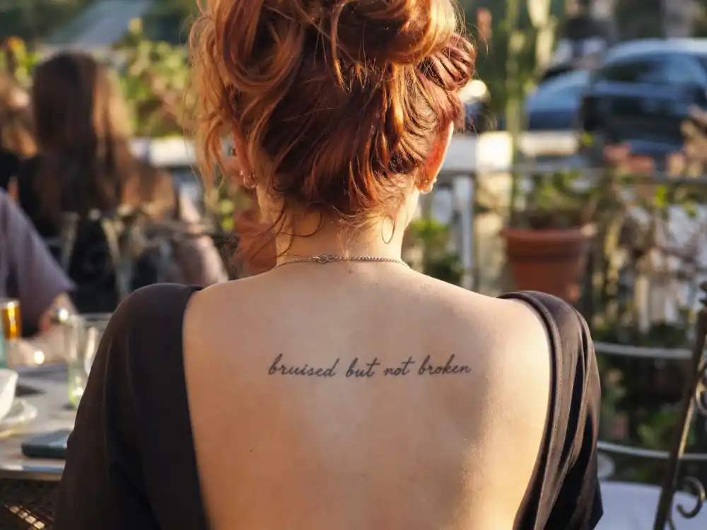 Bella Thorne tattoos and their meanings — colorful back tattoo photographed from behind in mirror selfie style