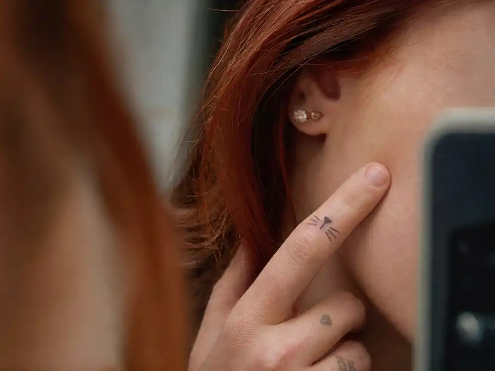 Bella Thorne tattoos and their meanings — cat portrait tattoo on forearm in editorial over-shoulder angle