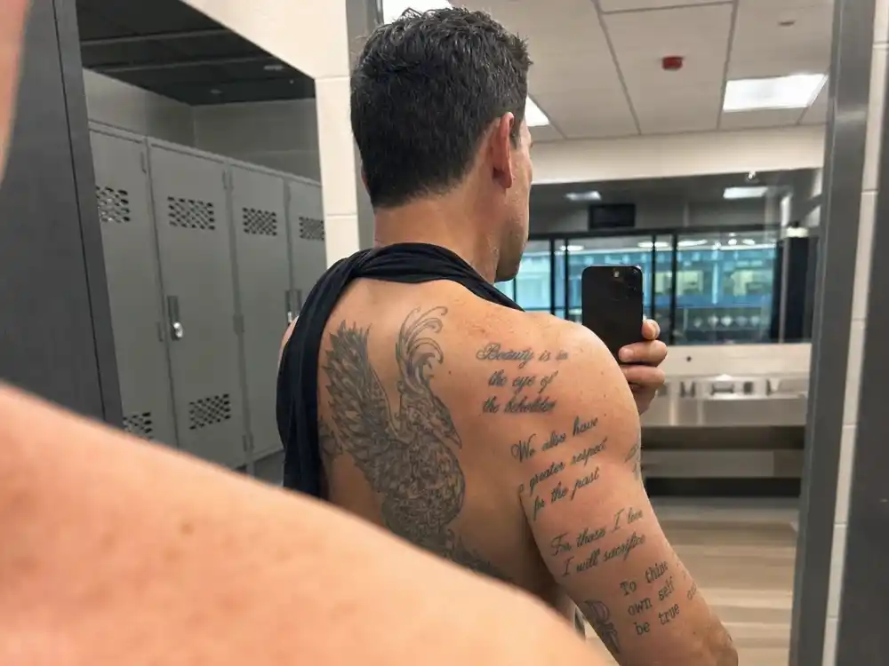 Ben Affleck tattoos and their meanings — shoulder script tattoos and phoenix edge visible in locker room mirror