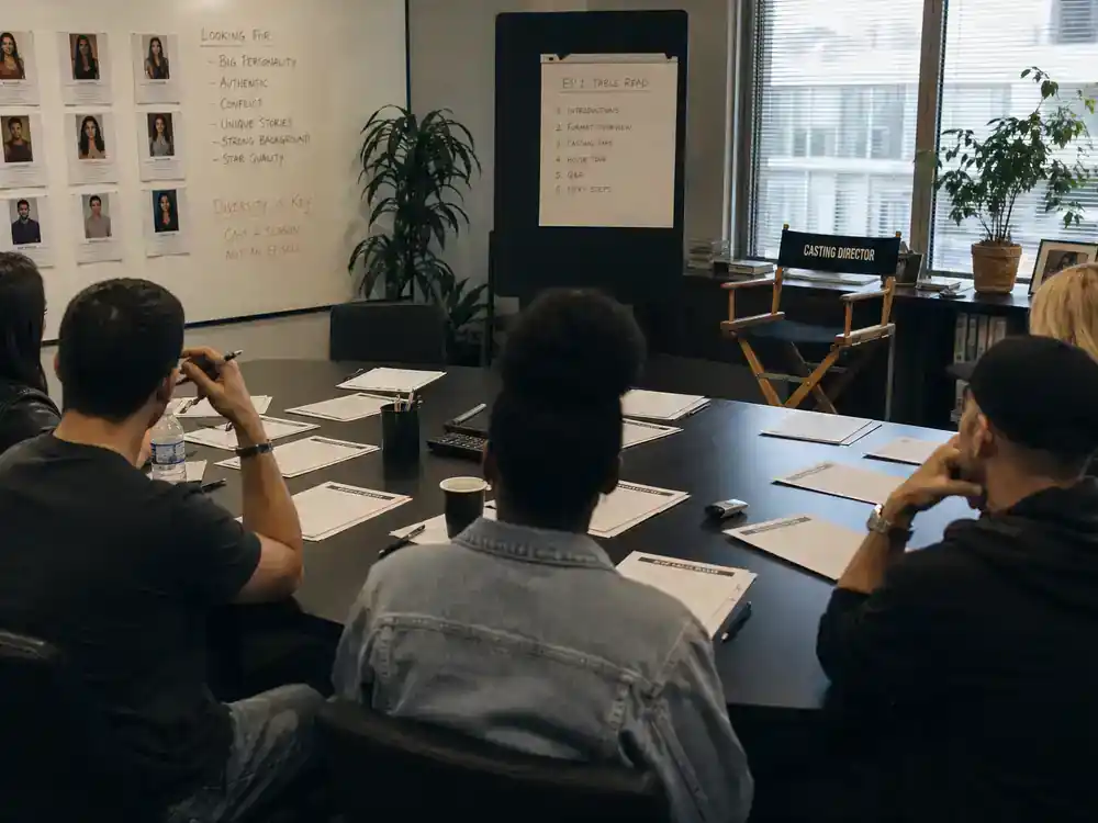 Big Brother 2026 cast and house preview cast — houseguest actor silhouettes from behind at competition reality TV casting table read with headshots and script pages