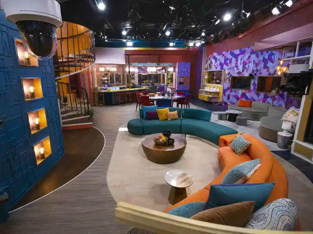 Big Brother 2026 cast and house preview house — colorful competition reality TV interior set with wall cameras fish-eye lens and modern living room awaiting cast move-in