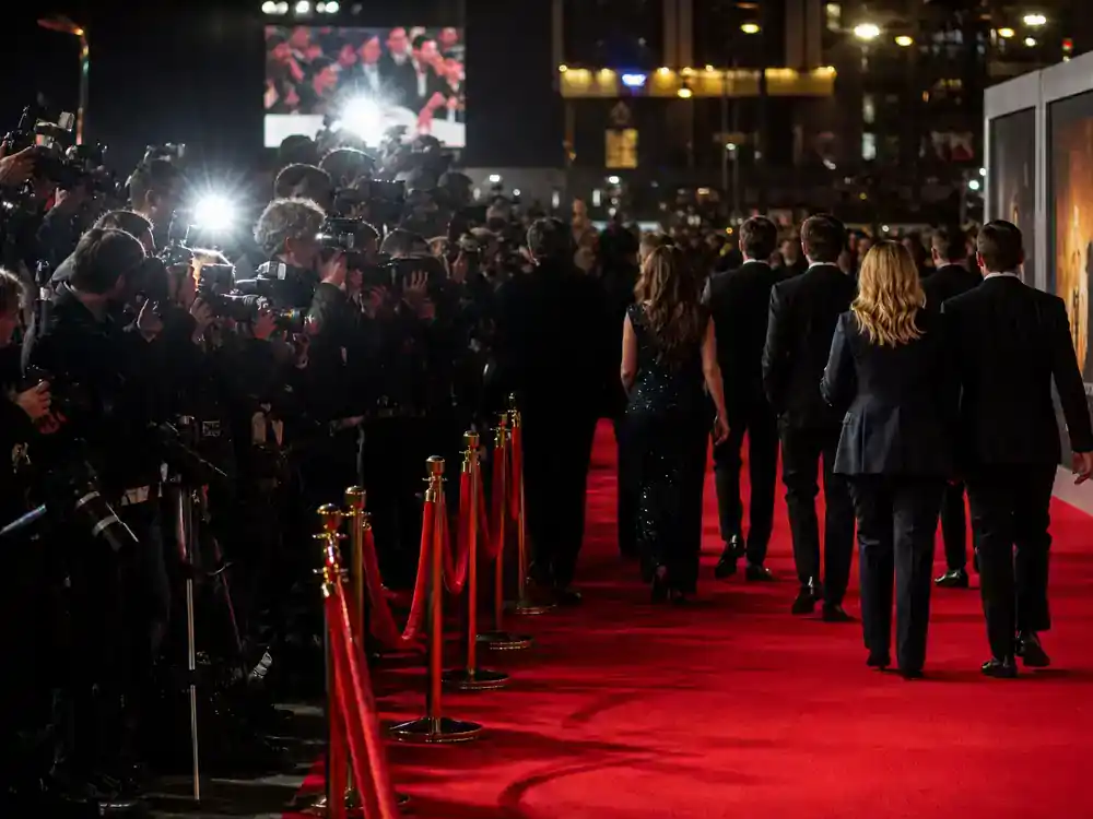 Biggest box office movies of 2026 so far blockbuster premiere — red carpet press photographers toward ensemble cast silhouettes from behind