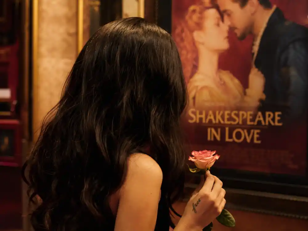 Camila Cabello tattoos and their meanings Shakespeare — pinky finger script tattoo at vintage movie theater with rose and romantic film poster