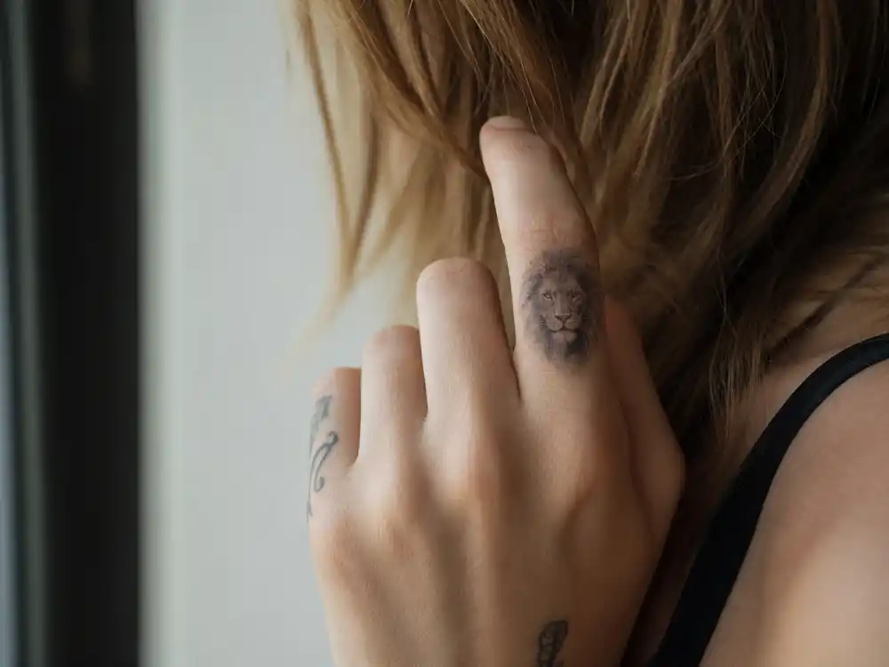 Cara Delevingne tattoos and their meanings — close-up of detailed lion head tattoo on index finger her first ink from May 2013