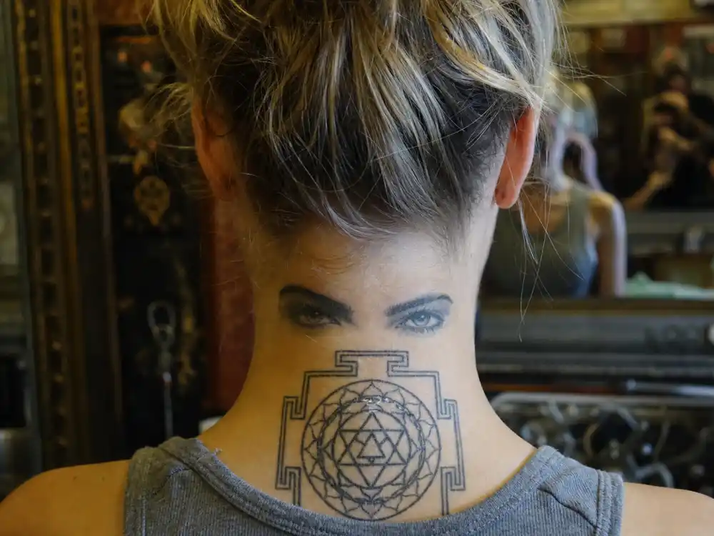 Cara Delevingne tattoos and their meanings — sak yant yantra tattoo on back of neck first seen at sister Poppy wedding