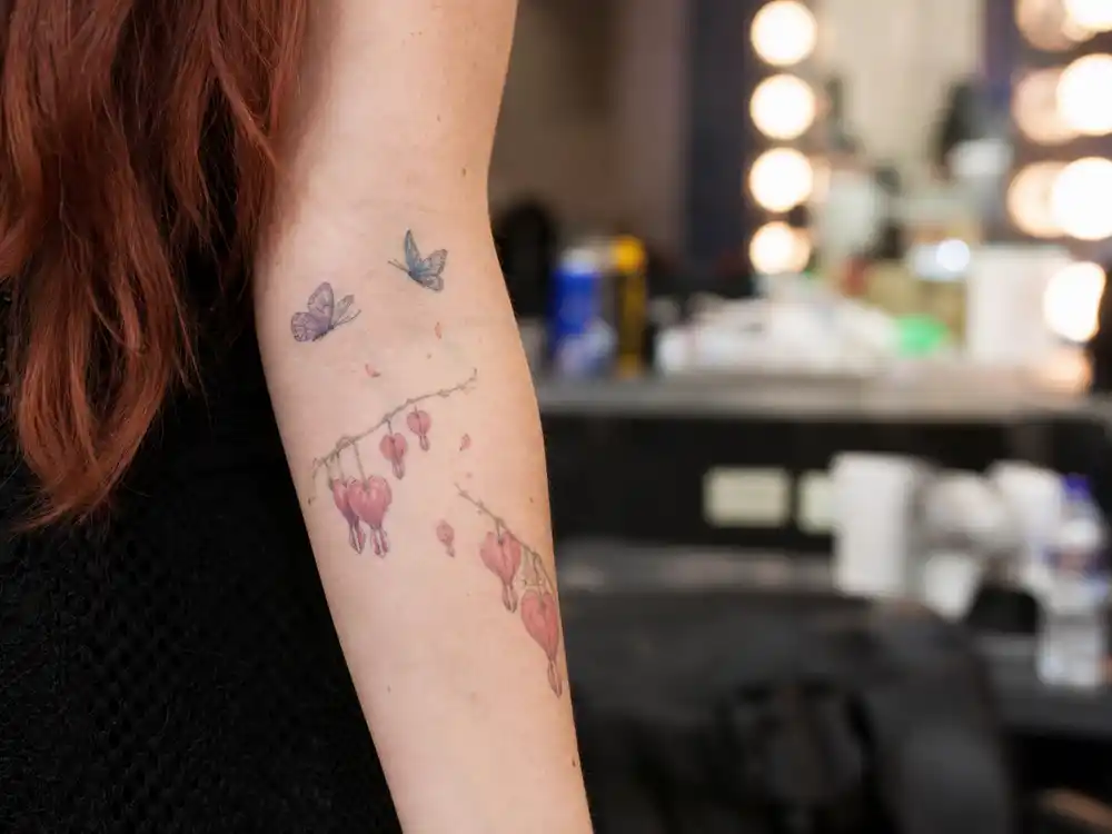 Chappell Roan tattoos and their meanings floral arm — hearts flowers and butterflies tattoo cluster on left forearm at dressing room