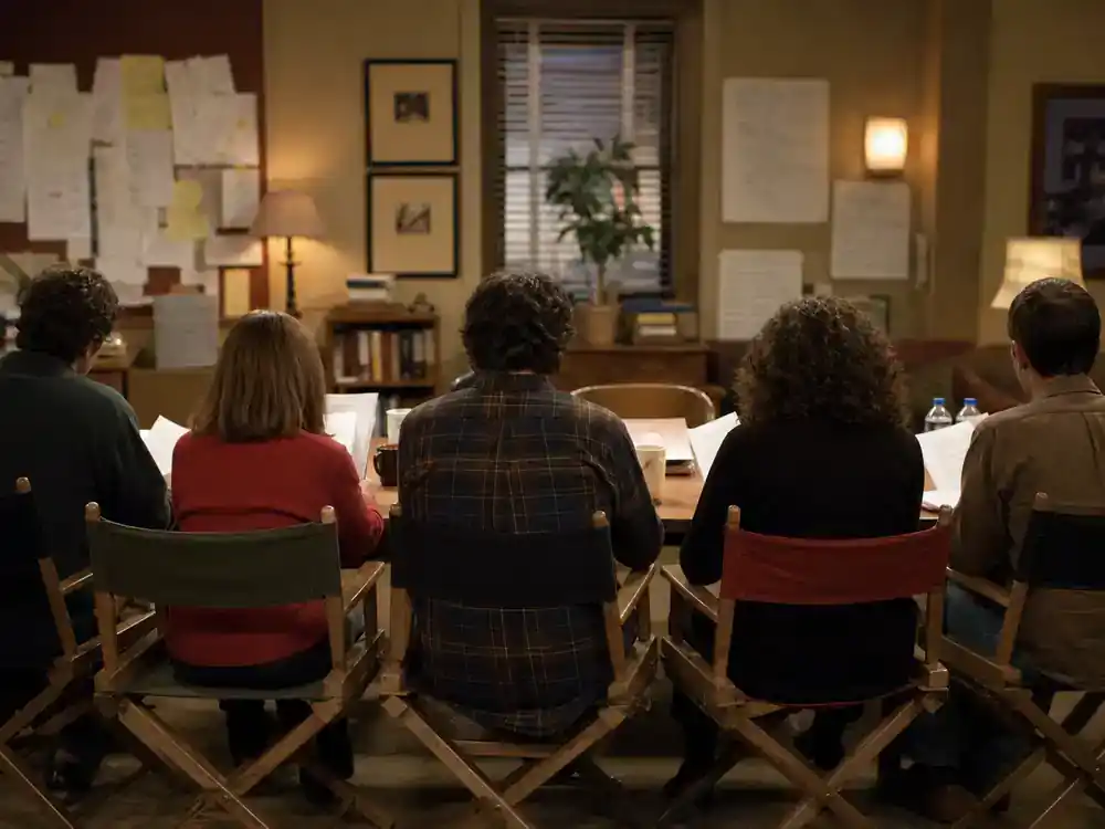 child actors from 90s sitcoms cast reunion guide ensemble table read — cast silhouettes from behind at sitcom rehearsal with director chairs and script pages warm office lighting